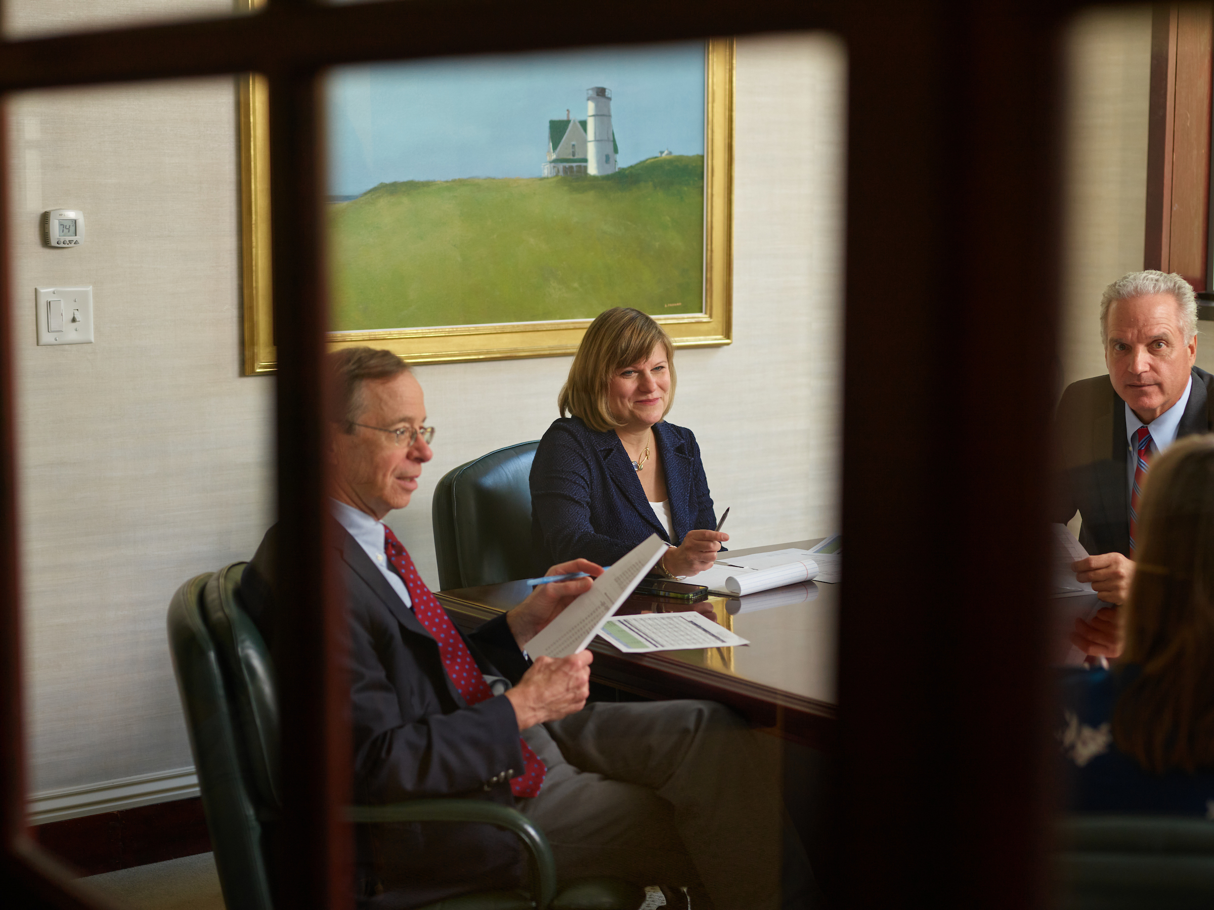 Three people around a table in business attire looking over documents